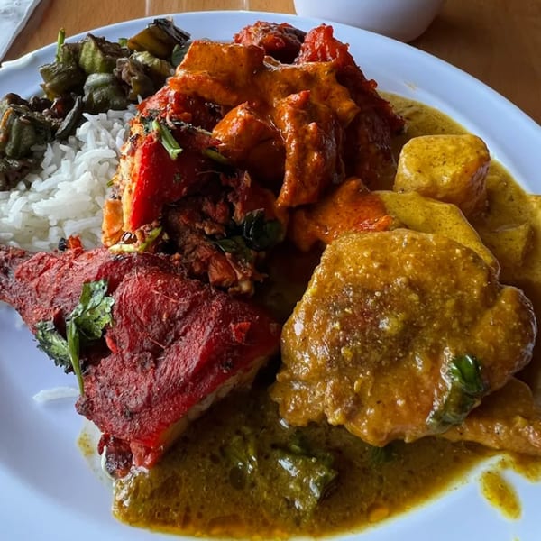 A vibrant Indian platter with tandoori chicken, butter chicken, saag, rice, and okra.